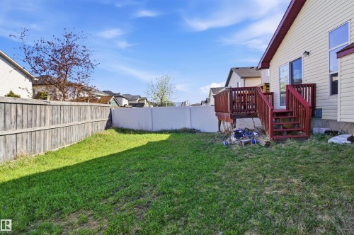 Expansive lawn area featuring a wood fence, a white vinyl fence, and a multi-level wood deck with stairs and railings - 16204 48 Street, Edmonton, AB - Outdoor