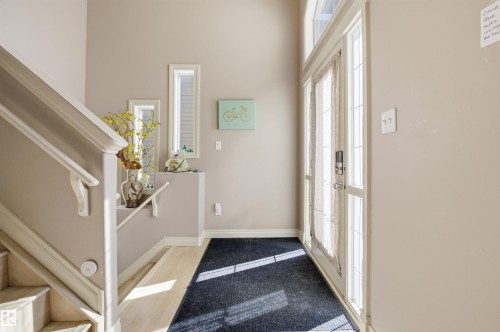 Front entry featuring a full-light door with transom window, light-toned wood-finish flooring, and a staircase with white balusters - 16204 48 Street, Edmonton, AB - Indoor Photo Showing Other Room