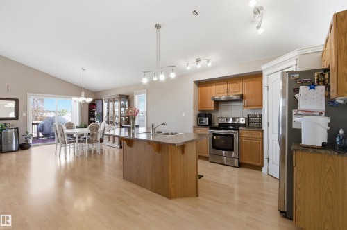 Open-concept living space featuring wood-finish flooring, a vaulted ceiling, and a kitchen island with an integrated sink - 16204 48 Street, Edmonton, AB - Indoor Photo Showing Kitchen With Double Sink