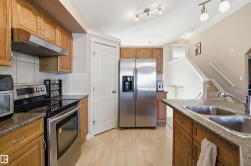 Kitchen featuring wood-finish cabinetry and light wood-finish flooring - 16204 48 Street, Edmonton, AB - Indoor Photo Showing Kitchen With Double Sink