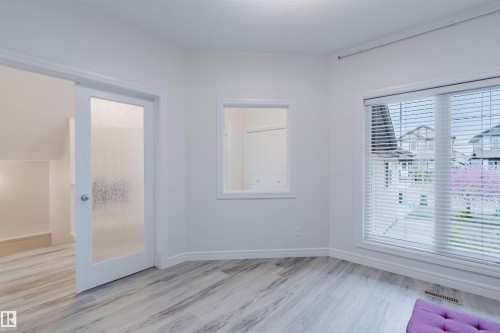 Room featuring light wood-finish flooring, white walls, and a large window with blinds - 17718 5A Avenue, Edmonton, AB - Indoor