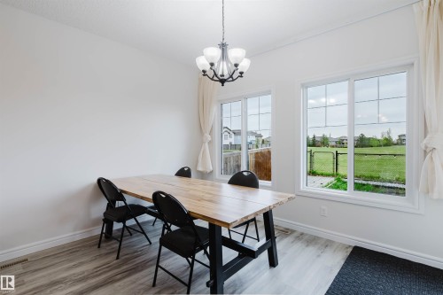 Dining area featuring light wood-finish flooring, white baseboards, and a contemporary chandelier - 17718 5A Avenue, Edmonton, AB - Indoor Photo Showing Dining Room