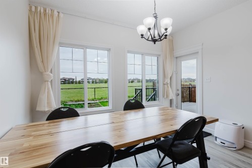 Dining area featuring wood-finish flooring, a contemporary chandelier, and a glass-paneled door leading to an outdoor deck - 17718 5A Avenue, Edmonton, AB - Indoor Photo Showing Dining Room