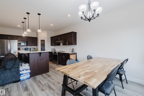 Open-concept kitchen and dining area featuring dark wood cabinetry and stainless steel appliances - 17718 5A Avenue, Edmonton, AB - Indoor