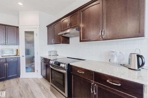 Modern kitchen featuring rich wood-finish cabinetry and light-toned countertops - 17718 5A Avenue, Edmonton, AB - Indoor Photo Showing Kitchen