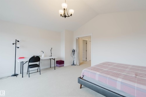 Spacious room featuring vaulted ceilings, light-toned carpeting, and a wrought iron chandelier - 17718 5A Avenue, Edmonton, AB - Indoor Photo Showing Bedroom