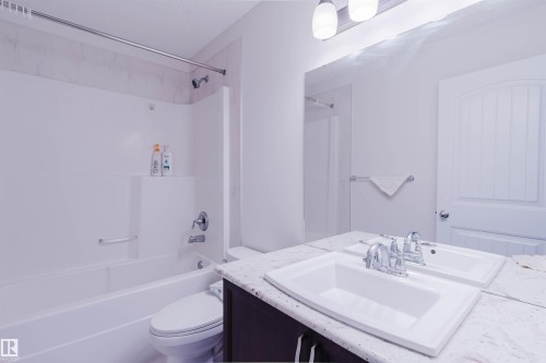 Bathroom featuring a white integrated tub and shower unit with a chrome showerhead and faucet - 17718 5A Avenue, Edmonton, AB - Indoor Photo Showing Bathroom