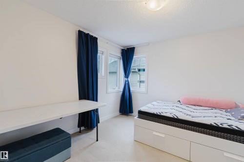Bright room featuring two windows with white trim, light neutral wall paint, and a textured ceiling - 17718 5A Avenue, Edmonton, AB - Indoor Photo Showing Bedroom