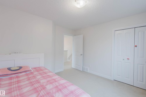 Carpeted room featuring white walls, a white paneled bed frame, and a bi-fold closet with white doors - 17718 5A Avenue, Edmonton, AB - Indoor Photo Showing Bedroom