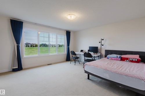 Spacious room featuring multiple windows, neutral wall tones, and carpeted flooring - 17718 5A Avenue, Edmonton, AB - Indoor Photo Showing Bedroom