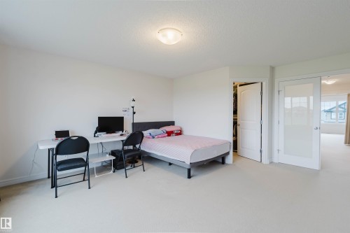 Spacious room featuring light-colored carpeting, white walls, a flush-mount ceiling light fixture, and a built-in closet with a white paneled door - 17718 5A Avenue, Edmonton, AB - Indoor Photo Showing Bedroom