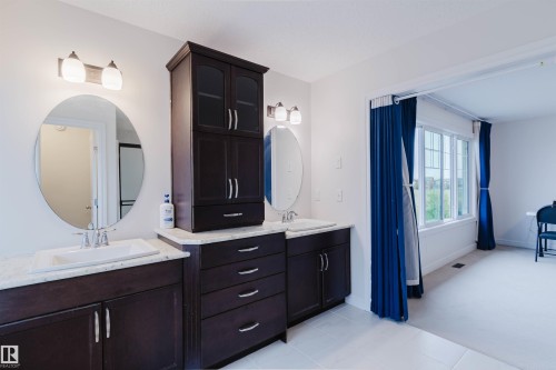 Double vanity with dark wood-finish cabinetry, white countertop, and under-mount sinks - 17718 5A Avenue, Edmonton, AB - Indoor Photo Showing Bathroom