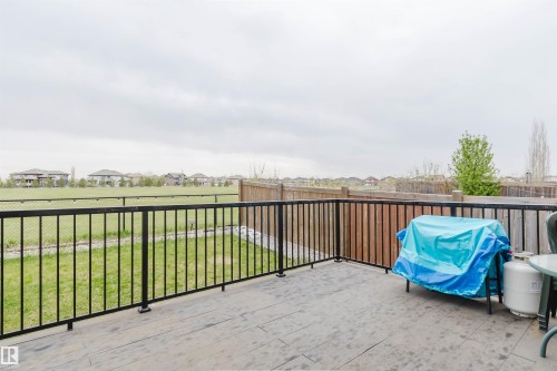 Spacious deck with dark gray surface, black metal railing, and a wood privacy fence - 17718 5A Avenue, Edmonton, AB - Outdoor