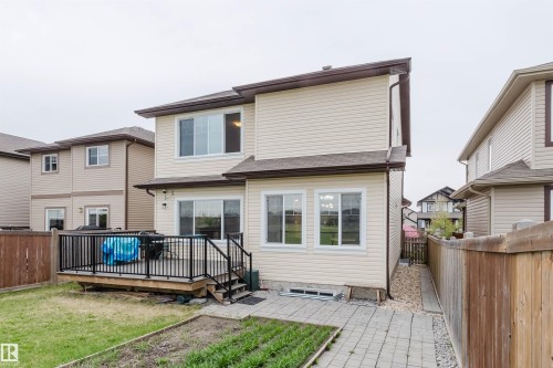 Rear exterior featuring a spacious wooden deck with black metal railings, a sliding glass door, and multiple windows - 17718 5A Avenue, Edmonton, AB - Outdoor With Exterior