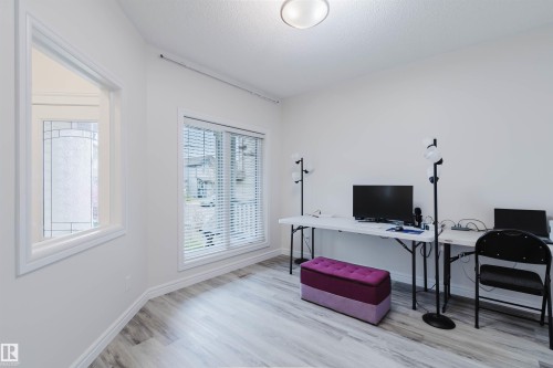 Neutral-toned interior room featuring wood-finish flooring, white walls, and a recessed ceiling light - 17718 5A Avenue, Edmonton, AB - Indoor Photo Showing Office