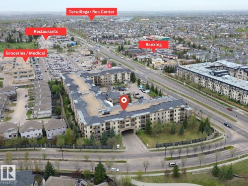 Aerial perspective highlighting the condominium building's proximity to diverse commercial establishments including grocery stores, medical facilities, restaurants, and banking services - 442 160 Magrath Road, Edmonton, AB - Outdoor With View