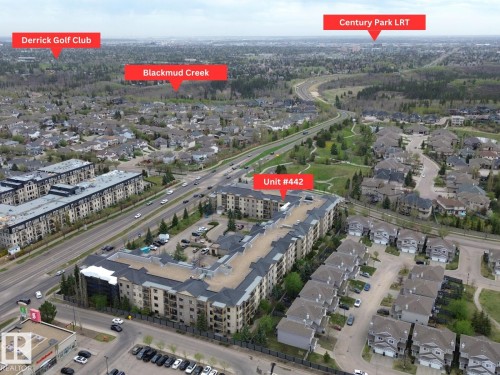 Multi-story residential building with a dark shingled roof, surrounded by paved roadways and green spaces - 442 160 Magrath Road, Edmonton, AB - Outdoor With View