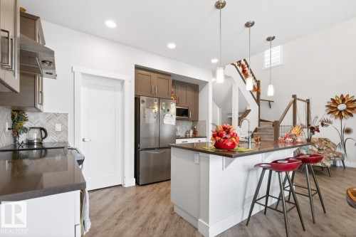 Kitchen featuring stainless steel appliances, dark countertops, and a herringbone tile backsplash - 7942 Erasmus Crescent, Edmonton, AB - Indoor Photo Showing Kitchen With Upgraded Kitchen