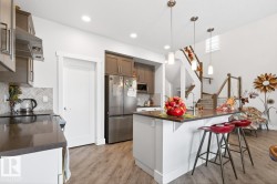 Kitchen featuring stainless steel appliances, dark countertops, and a herringbone tile backsplash - 