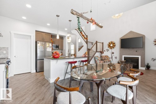 Open-concept living area featuring high ceilings and wood-finish flooring - 7942 Erasmus Crescent, Edmonton, AB - Indoor With Fireplace
