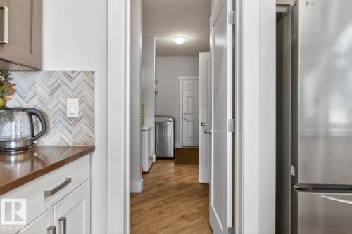 Kitchen counter with herringbone tile backsplash and built-in stainless steel refrigerator - 7942 Erasmus Crescent, Edmonton, AB - Indoor Photo Showing Other Room