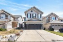 Two-story residence featuring light-toned horizontal siding, a prominent front-facing gable, and a two-car garage with a dark panel door - 7942 Erasmus Crescent, Edmonton, AB  - Outdoor With Facade 