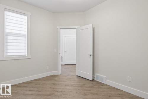 Spacious room featuring wood-finish flooring, white trim, and a window with horizontal blinds - 7942 Erasmus Crescent, Edmonton, AB - Indoor Photo Showing Other Room
