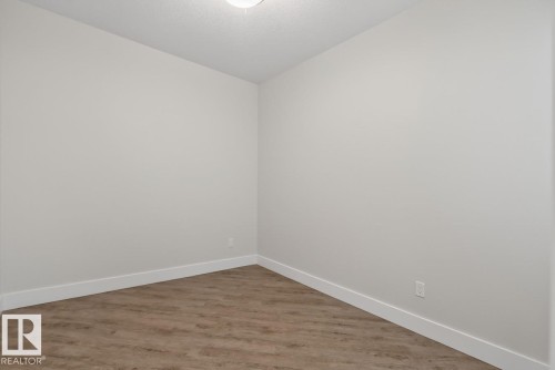 Neutral-toned interior with wood-finish flooring - 7942 Erasmus Crescent, Edmonton, AB - Indoor Photo Showing Other Room