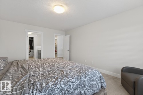 Carpeted bedroom featuring neutral wall tones, white trim, and a flush-mount ceiling light - 7942 Erasmus Crescent, Edmonton, AB - Indoor Photo Showing Bedroom
