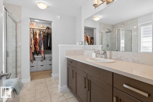 Bathroom featuring a spacious walk-in closet, a vanity with ample counter space, a large mirror, a glass-enclosed shower, and tile flooring - 7942 Erasmus Crescent, Edmonton, AB - Indoor Photo Showing Bathroom