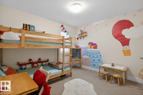 Carpeted room featuring a ceiling-mounted light fixture, bunk beds with wooden frames, and walls adorned with decorative murals - 7942 Erasmus Crescent, Edmonton, AB - Indoor Photo Showing Bedroom
