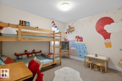 Carpeted room featuring a ceiling-mounted light fixture, bunk beds with wooden frames, and walls adorned with decorative murals - 