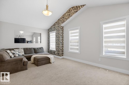 Vaulted ceiling with an accent wall featuring patterned wallpaper - 7942 Erasmus Crescent, Edmonton, AB - Indoor Photo Showing Living Room
