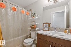 Bathroom featuring a white toilet, full-sized bathtub with a clear shower curtain, and an over-toilet storage unit - 
