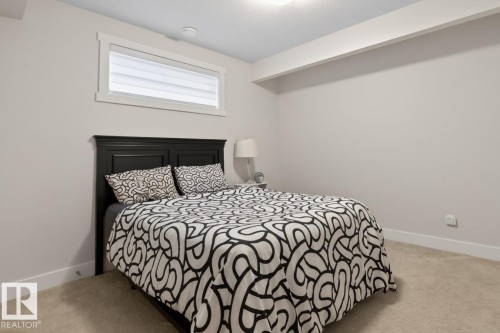 Carpeted room featuring a high window with white trim, a flush-mount ceiling light, and a white baseboard - 7942 Erasmus Crescent, Edmonton, AB - Indoor Photo Showing Bedroom