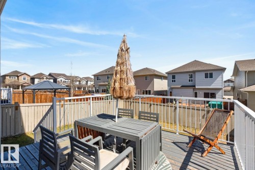 Spacious wood deck featuring white railings, a clear glass panel railing section, and a wood privacy fence - 7942 Erasmus Crescent, Edmonton, AB - Outdoor With Exterior