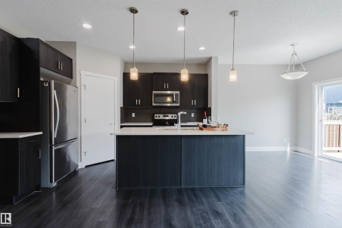 Kitchen featuring dark wood-finish cabinetry, stainless steel appliances, and a central island with a white countertop - 2839 Koshal Crescent, Edmonton, AB - Indoor Photo Showing Kitchen With Stainless Steel Kitchen With Upgraded Kitchen