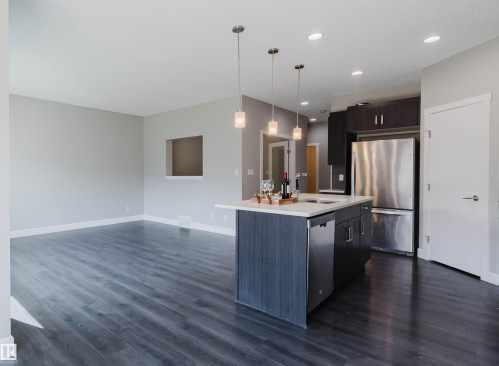 Modern kitchen island featuring a light-toned countertop and pendant lighting - 2839 Koshal Crescent, Edmonton, AB - Indoor Photo Showing Kitchen With Stainless Steel Kitchen With Upgraded Kitchen