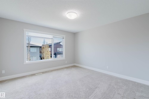 Bright room featuring neutral carpeting, a large window, white trim, and a flush-mount ceiling light - 2839 Koshal Crescent, Edmonton, AB - Indoor Photo Showing Other Room