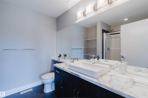 Modern bathroom featuring a dark wood-finish vanity with a white marble-look countertop, an integrated rectangular vessel sink, and chrome fixtures - 2839 Koshal Crescent, Edmonton, AB - Indoor Photo Showing Bathroom