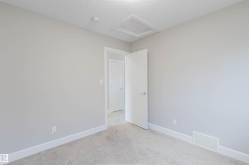 Neutral wall paint, plush carpet, white trim throughout, and a modern white door with a polished nickel handle - 2839 Koshal Crescent, Edmonton, AB - Indoor Photo Showing Other Room