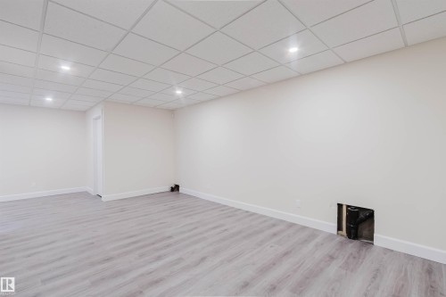 Spacious room featuring light wood-finish flooring, white baseboards, and a grid ceiling with recessed lighting - 2839 Koshal Crescent, Edmonton, AB - Indoor Photo Showing Other Room