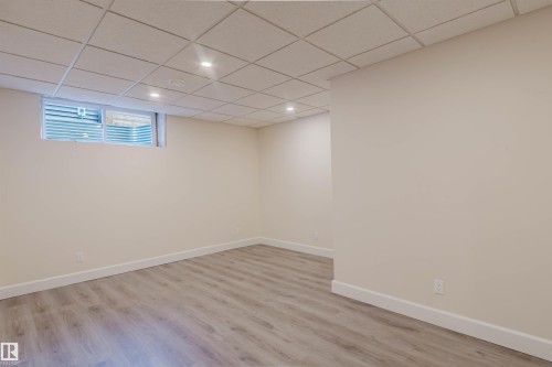 Room featuring recessed lighting, a drop ceiling, wood-finish flooring, a window, and neutral wall tones - 2839 Koshal Crescent, Edmonton, AB - Indoor
