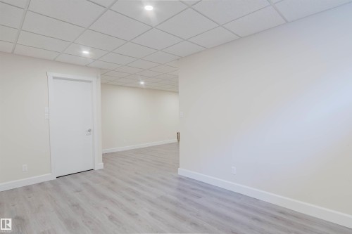 Spacious room featuring light-toned wood-finish flooring, white walls, and a dropped ceiling with integrated recessed lighting - 2839 Koshal Crescent, Edmonton, AB - Indoor Photo Showing Other Room