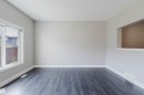 Spacious room featuring dark wood-finish flooring, light neutral-toned walls, white baseboards, and a large window with white trim - 2839 Koshal Crescent, Edmonton, AB  - Indoor Photo Showing Other Room 