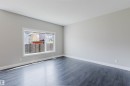 Spacious room featuring dark wood-finish flooring, light gray wall paint, white baseboards, and a large window with white trim - 2839 Koshal Crescent, Edmonton, AB  - Indoor Photo Showing Other Room 