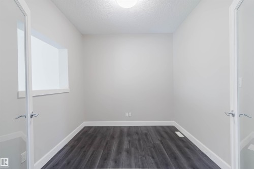 Room featuring wood-finish flooring, light grey painted walls, white baseboards, and a ceiling light fixture - 2839 Koshal Crescent, Edmonton, AB - Indoor Photo Showing Other Room