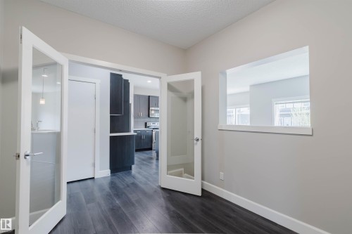 Wood-finish flooring throughout, featuring a pass-through opening and French doors with glass inserts - 2839 Koshal Crescent, Edmonton, AB - Indoor Photo Showing Other Room