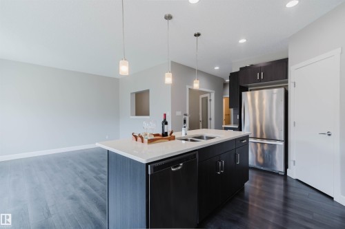 Kitchen featuring an island with a light-toned countertop, dual sinks, and a built-in dishwasher - 2839 Koshal Crescent, Edmonton, AB - Indoor Photo Showing Kitchen With Double Sink With Upgraded Kitchen