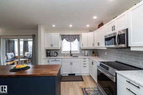 Kitchen featuring white cabinetry, stainless steel appliances, grey subway tile backsplash, and quartz countertops - 25 1904 Mill Woods Road Road, Edmonton, AB - Indoor Photo Showing Kitchen With Upgraded Kitchen